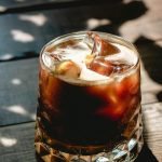 Close-up of a refreshing iced cold brew coffee in a glass with sunlight and shadows.