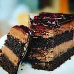 Close-up of a rich chocolate cake slice with blueberry topping, perfect for dessert lovers.