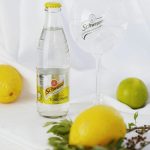 Still life of Schweppes tonic water with lemons and limes for a refreshing cocktail setup.